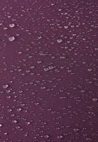 Wodoodporny materiał w głębokim fioletowym kolorze, z licznymi przezroczystymi kroplami wody na gładkiej powierzchni. Teksturowany małymi wgnieceniami i odbiciem światła.
