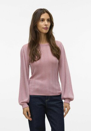 Maglione a coste rosa chiaro con maniche lunghe e a sbuffo, realizzato in un materiale scintillante, abbinato a jeans blu scuro.