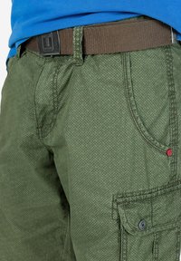 Grüne Cargo-Shorts mit einem strukturierten Muster. Enthält einen braunen Gürtel und eine Seitenasche mit einem Knopfdetail.