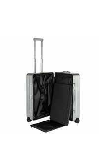 Valise rigide argentée avec une poignée télescopique et des roulettes doubles. L'intérieur est doté d'un revêtement noir, de sangles et d'un compartiment de rangement amovible.