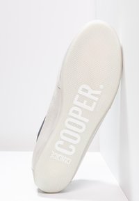 Sneaker bianca con tomaia in pelle liscia, suola in gomma e fondo testurizzato con il marchio "COOPER" in lettere grandi.