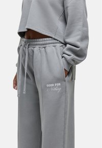 Grijze cropped sweatshirt en bijpassende sweatpants met elastische taille, zijzakken en geborduurde tekst "GOOD FOR Nothing". Zachte stoftextuur.