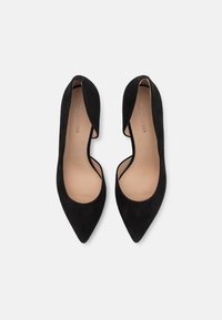 Scarpe con tacchi alti in suede nero con punta affilata e lati aperti, dotate di una fodera interna liscia e design minimalista.