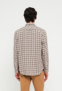 Καρό μακρυμάνικο πουκάμισο σε καφέ και κρεμ χρώματα με μανσέτες με κουμπιά, καμπυλωτό τελείωμα και γιακά, κατασκευασμένο από ελαφρύ ύφασμα.