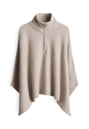 Beige knitted poncho with high ribbed collar and front half-zip, draped hem, and wide sleeves, designed for layering and warmth.