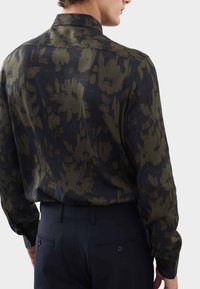 Langärmliges Hemd in Dunkelgrün mit floralem Muster. Weicher Stoff, klassischer Kragen und kontrastierende dunkelnavy Akzente auf der Rückseite.