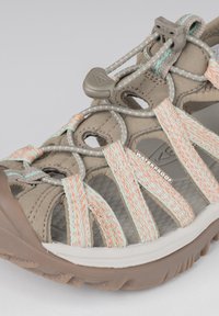 Beige waterproof sandal with colorful woven straps, featuring a grey toggle for adjustment and a textured rubber sole for grip.