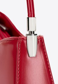 Czerwona skórzana torebka w rygorystycznym designie, o gładkiej fakturze i metalowych akcentach przy zamku błyskawicznym.