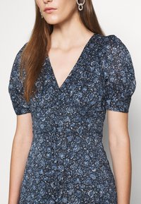 Vestido floral azul marino con escote en V, mangas cortas abullonadas, tejido texturizado y sutiles acentos brillantes, con intrincados patrones florales.