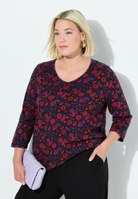 Schwarzes T-Shirt mit einem Paisley- und Floral-Muster in Rot, Lila und Weiß. Mit V-Ausschnitt und drei Viertelärmel.