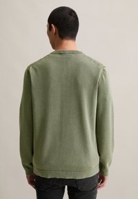 Zielony sweter robiony na drutach, z okrągłym dekoltem, teksturowana tkanina, prążkowane mankiety i dół, o luźnym kroju. Widoczne detale szycia na ramionach.