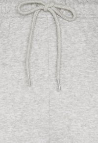 Ljusgrå mjukisbyxor i mjukt tyg; har dragsko i midjan och en subtil textur. Inga mönster eller extra detaljer synliga.