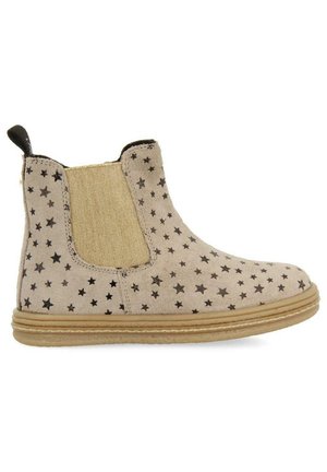 Botas de tobillo beige con patrones de estrellas negras, paneles laterales elásticos y una suave textura de ante. Suela de goma y tirador para ponérselas fácilmente.