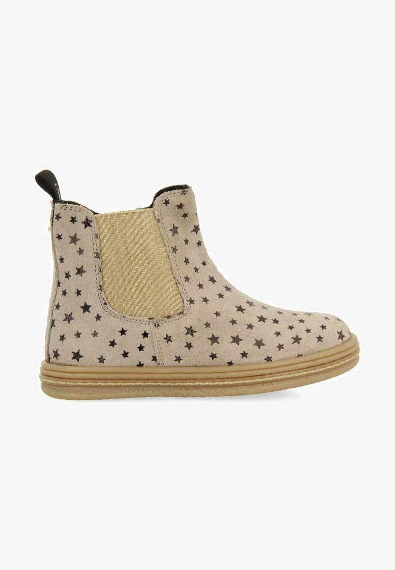 Bottines beiges avec des motifs d'étoiles noirs, panneaux latéraux élastiques et une texture en daim douce. Semelle en caoutchouc et languette pour un enfilage facile.
