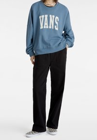 Niebieska bluza z kapturem z logo "VANS", czarne szerokie spodnie oraz czarno-białe trampki w szachownicę. Miękki materiał, luźny krój.