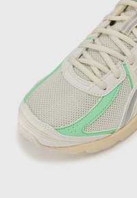 Hellbeige Sneaker aus Mesh-Gewebe mit mintgrünen Akzenten und grauen Details. Verfügt über eine strukturierte Sohle und eine beigen Gummilaufsohle.
