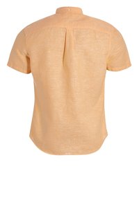 Camisa de manga corta en lino naranja claro con cuello abotonado, pliegue en la parte trasera y dobladillo curvado. Tejido texturizado y ligero.