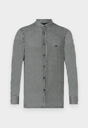 Striped long-sleeve shirt in black and white, featuring a band collar, button closure, and a small logo on the chest. Smooth fabric texture.