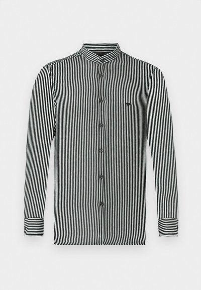 Csíkos, hosszú ujjú ing fekete és fehér színben, bandakolással, gombos záródással és egy kis logóval a mellkason. Simaságával kiemelkedő anyagtextúra.