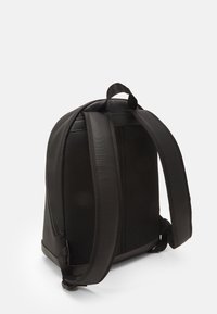 Zaino nero realizzato in materiale testurizzato, con pannelli laterali in rete, spallacci imbottiti e una maniglia superiore per una facile portabilità.