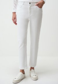 Witte denim broek met een recht gesneden ontwerp, mid-rise taille en klassieke vijf-pocket stijl, gecombineerd met witte sneakers.