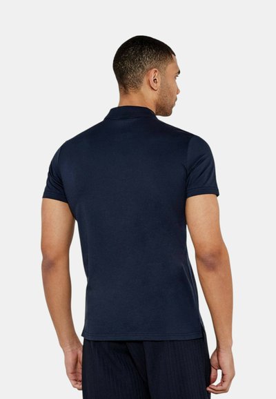 Polo shirt blu navy realizzato in cotone morbido, con colletto classico e maniche corte, mostrato dal retro, con vestibilità regolare.