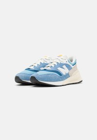 Baskets bleues avec une tige en suède et mesh, arborant des accents blancs et gris, une semelle épaisse et une semelle extérieure noire contrastante.