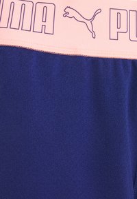 PUMA sportieve shorts met een gladde textuur, donkerblauwe kleur en een roze tailleband met logo en tekst in paars.