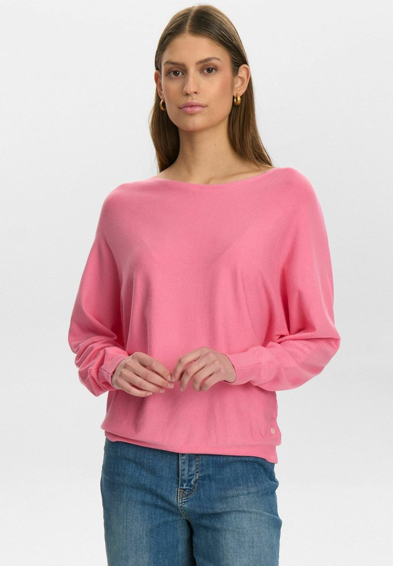 Maglione rosa a maniche lunghe con collo ampio, polsini a costine e una vestibilità rilassata, abbinato a jeans in denim blu. Materiale morbido e leggera texture.