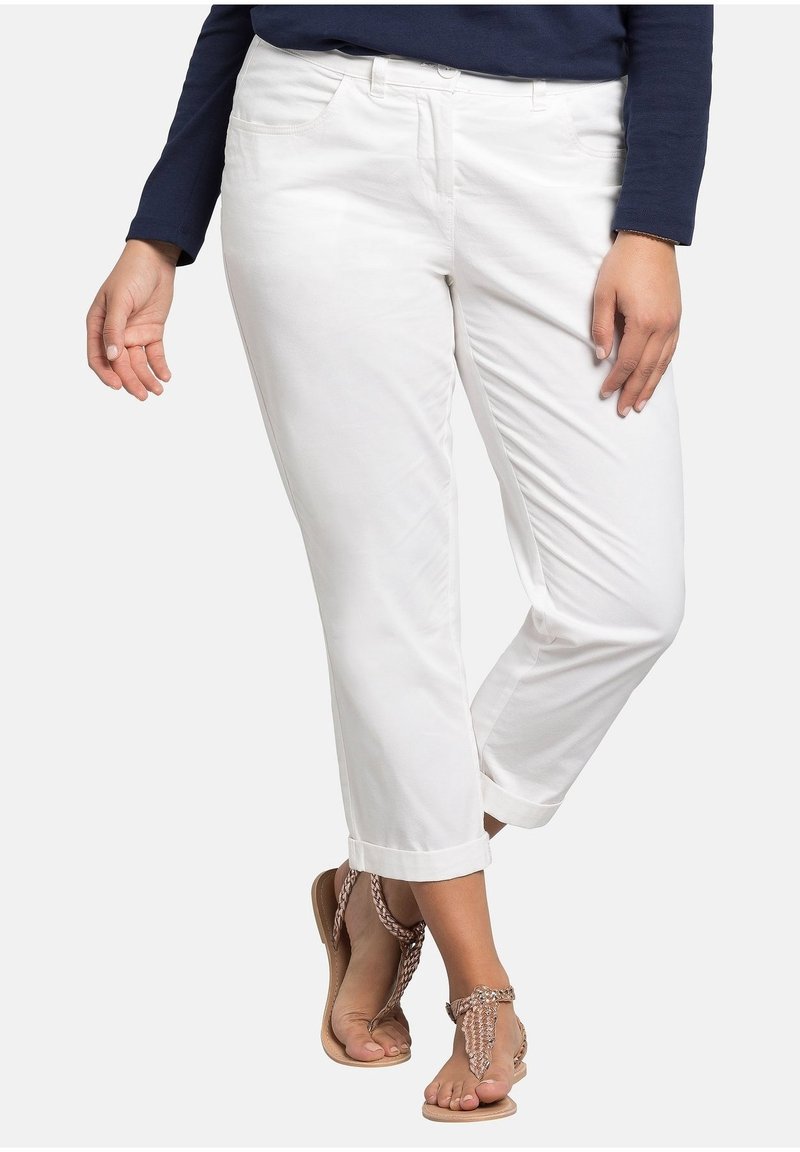 Witte cropped broek met een gladde textuur, ontworpen met voorzakken en opgerolde zoom, gecombineerd met platte sandaaltjes met banden.