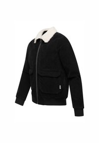 Zwarte corduroy jas met een witte nep-shearling kraag, twee voorzakken, ribgebreide manchetten en een volledige ritssluiting.