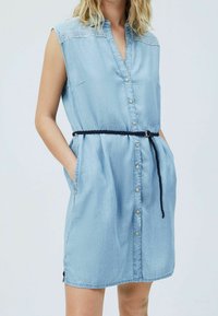 Light blue denim dress with a button-down front, short sleeves, and a braided black belt. Features side pockets and decorative stitching.