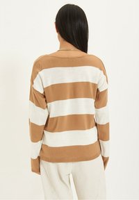 Gestreepte trui met afwisselend tan en witte horizontale strepen, met een relaxte pasvorm en gebreide textuur. Lange mouwen en een ronde halslijn.