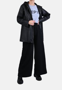 Chaqueta con capucha de cuero negro sobre una sudadera gris con el texto “EPT”, combinada con pantalones negros de pierna ancha y botas negras robustas.