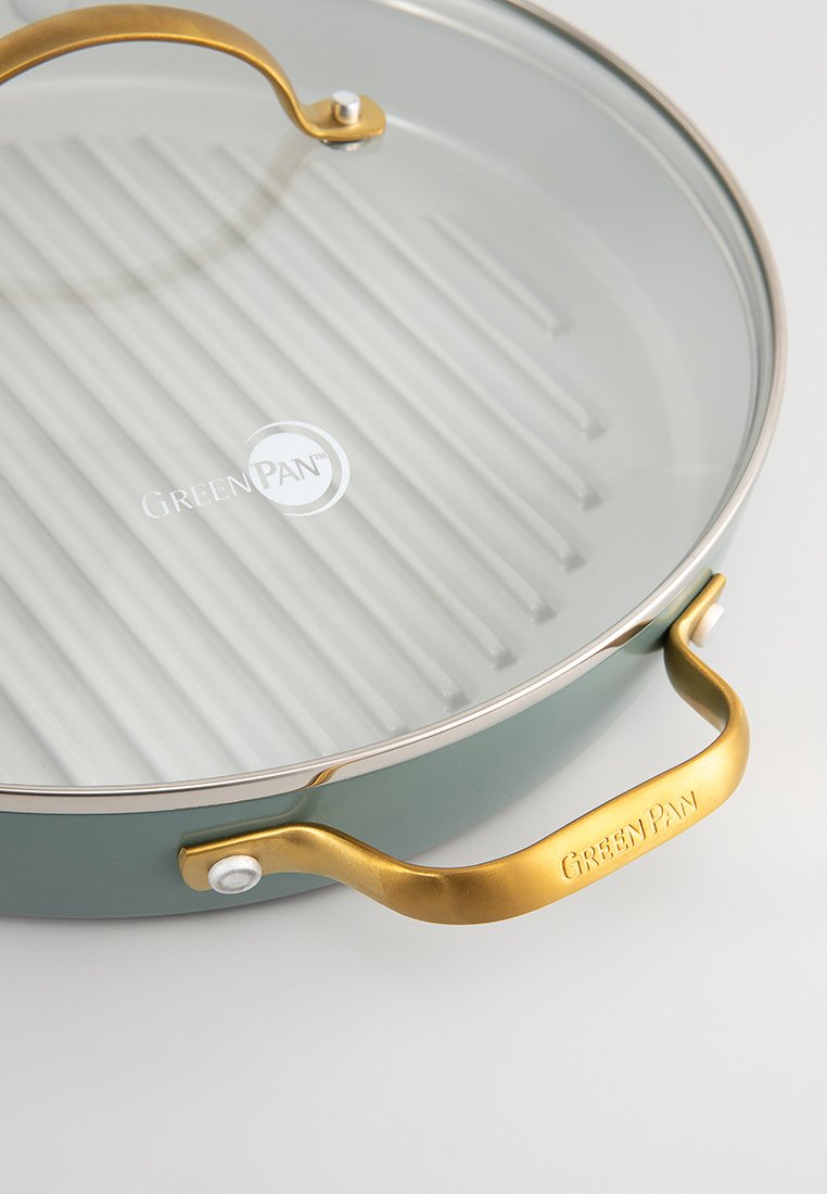 Poêle à griller GreenPan avec une surface en céramique striée. Équipée d'un couvercle en verre transparent et d'une poignée en métal doré avec logo. La couleur est teal.