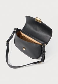 Black leather crossbody bag with adjustable strap, gold-tone clasp, open flap, and beige interior zip pocket against a white background.