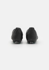 Les crampons de football noirs présentent une finition mate lisse, des crampons réglables et un design épuré avec des détails de logo en relief sur le talon.
