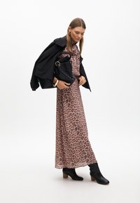 Maxime dress with pink leopard print, yhdistetty mustaan bleiseriin. Malli pitää mustaa teksturoitua käsilaukua ja käyttää mustia korkokenkiä.
