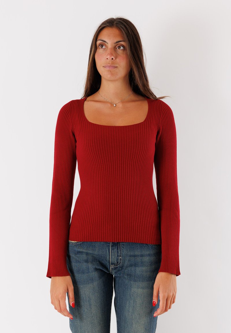 Maglione a maniche lunghe rosso a coste con scollo quadrato, design aderente e tessuto testurizzato, abbinato a jeans di denim blu.