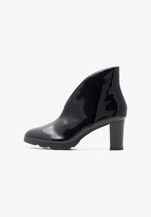 Botín de cuero negro charolado con punta afilada y tacón grueso. Textura suave y brillante con un diseño elegante.