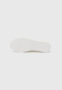 White sneaker sole with horizontal ridges for traction, featuring a smooth rounded toe and slightly raised heel design.