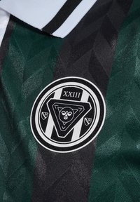 Svart och grön mönstrad tyg med en texturerad yta. Har en cirkulär logotyp med geometriska accenter och texten "XXIII" överst.