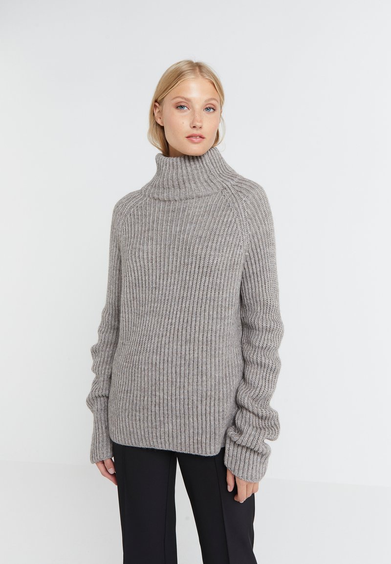 Grauer gerippter Rollkragenpullover mit lockerer Passform, langen Ärmeln mit verlängerten Bündchen und einem weichen, strukturierten Strickstoff.