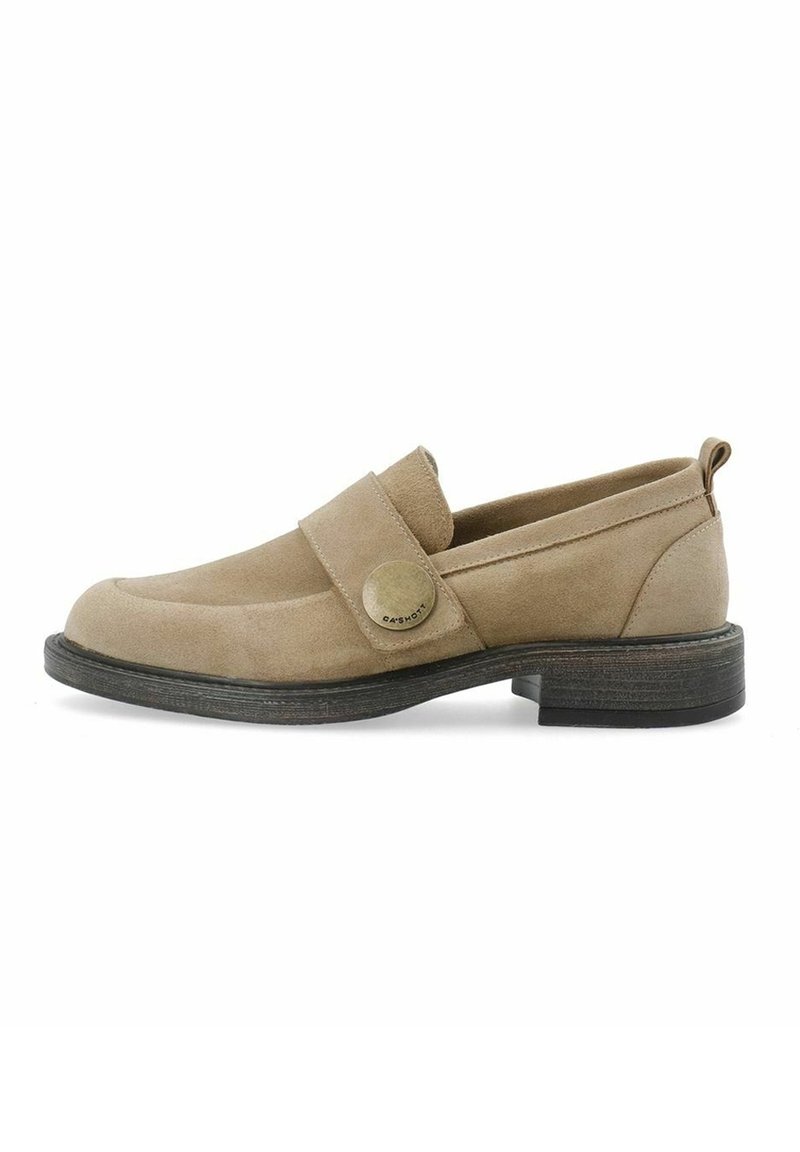 Mocassin en daim beige avec une semelle noire, un petit talon et une large bride ornée d'un bouton logo métallique rond sur le côté.