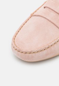 Lyserosa mokkasinsko, med rund tå, kontraststing og en jevn tekstur. Enkelt design med minimale detaljer.
