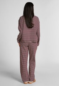 Gestreept loungenpak bestaande uit een losse top en wijde broek in bordeauxrood en lichtroze. Zachte stof met een gladde textuur.