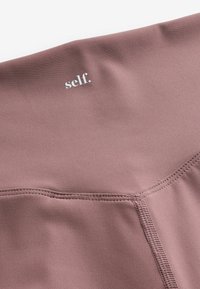 Kõrge vöökohaga spordileggings pehmest maavärvi kangast. Omab tasapinda õmblusi ja peent hõbedast logo "self." vööl.
