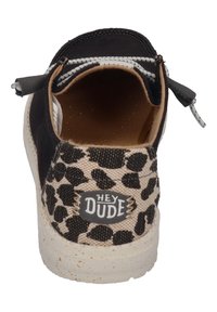 Black canvas slip-on shoe with tan leopard print accents, featuring a beige speckled sole and "HEY DUDE" logo on the side.