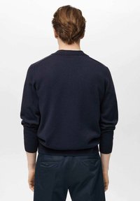 Mornarsko pleten pulover z rebrastimi manšetami in pasom; kroj s krožnim vratom; gladka tekstura, prilegajoč slog; oblečen z mornarskimi hlačami.