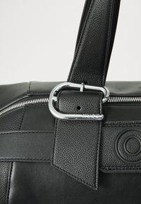 Black leather bag with textured surface. Features silver hardware, a zipper closure, and a prominent logo detail on the side.